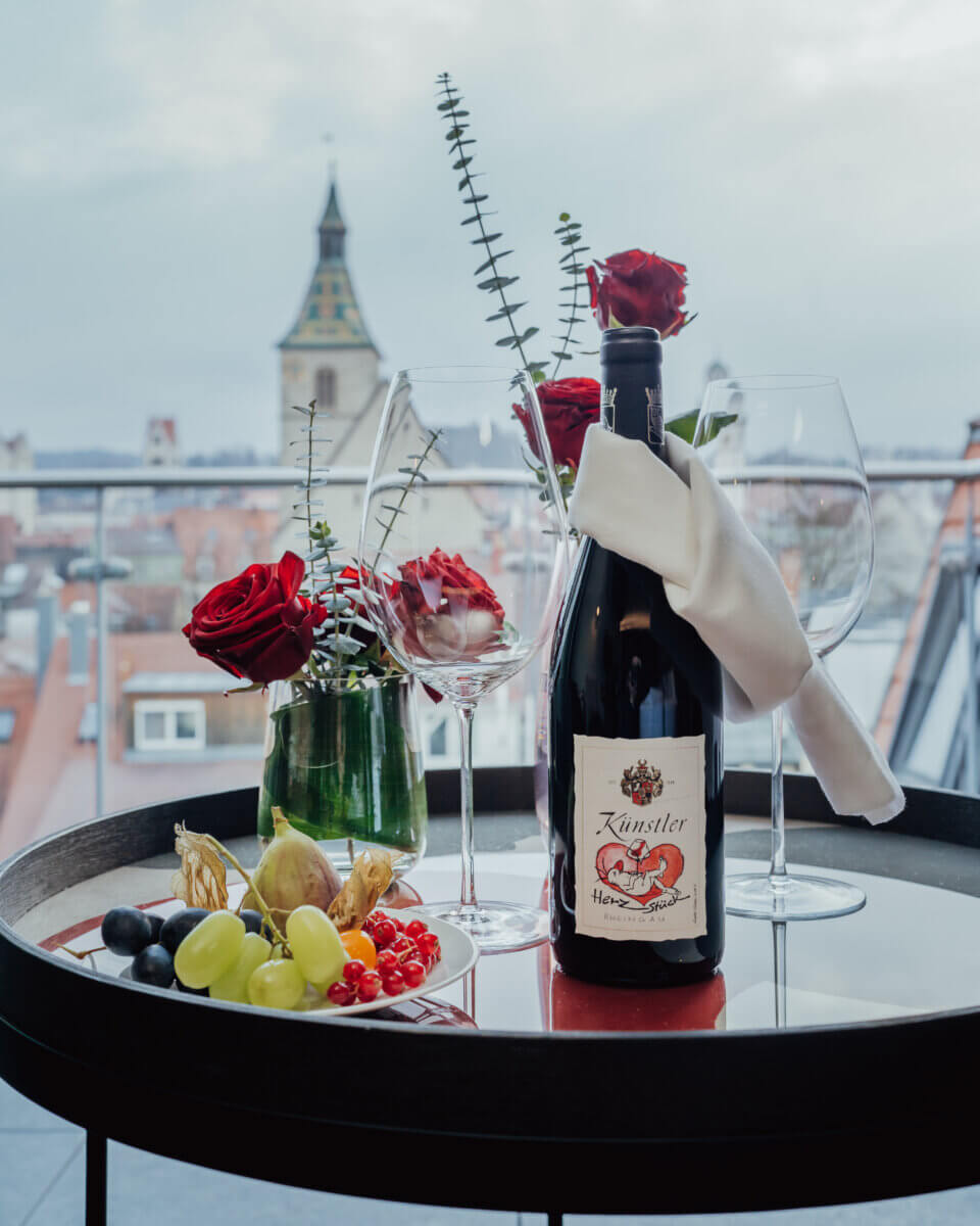 Flasche Wein mit zwei Weingläsern und Rosen auf dem Zimmer