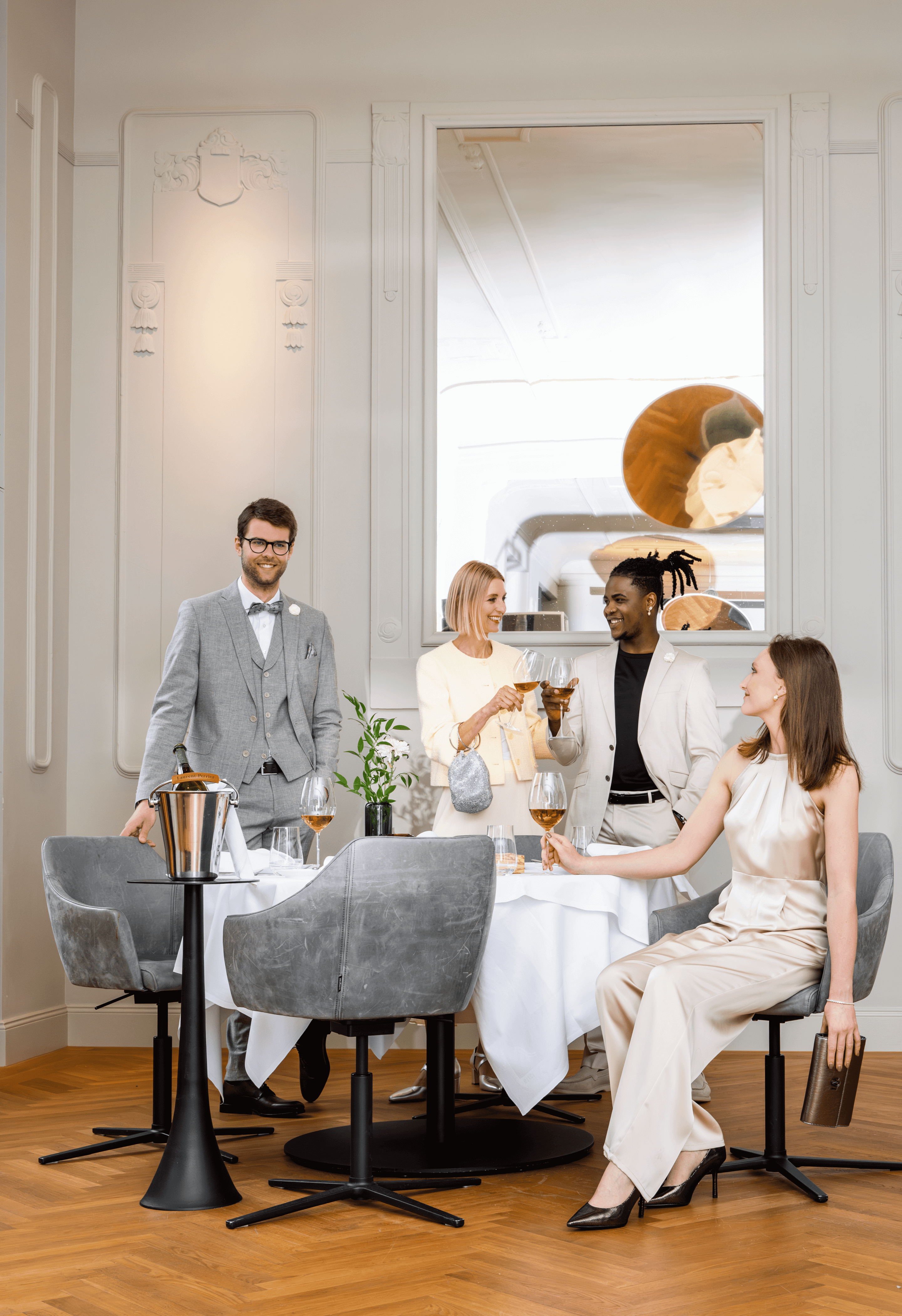 Vier stilvoll gekleidete Personen stehen beisammen, trinken gemeinsam Wein und genießen entspannt die gemeinsame Zeit in eleganter Atmosphäre im Kaisersaal